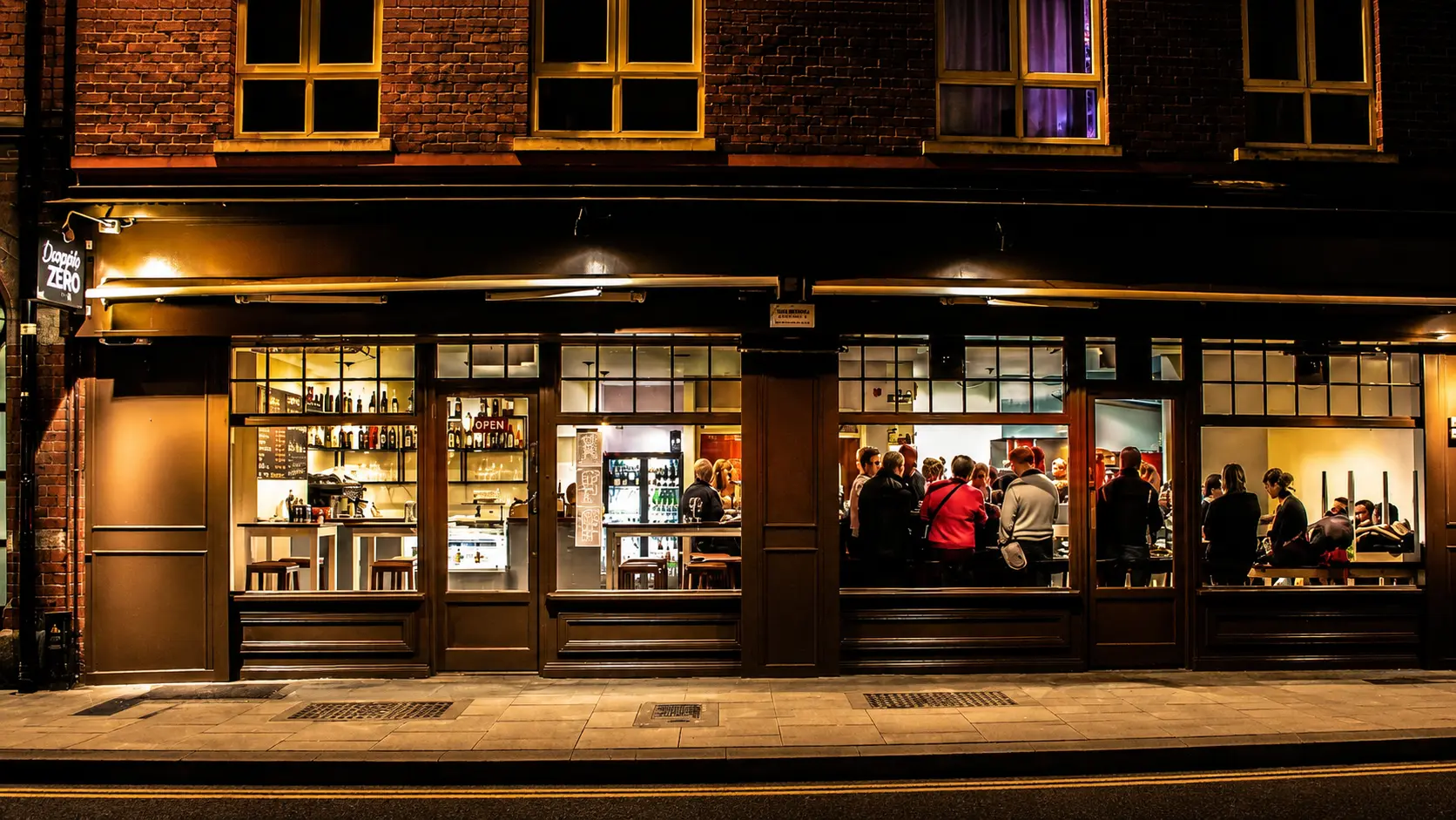 Doppio Zero Cafe exterior at night in Dublin with warm lighting and guests inside